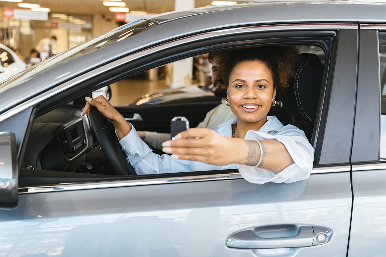 creative-03 Smiling woman sitting in her new car holding keys, celebrating purchase.