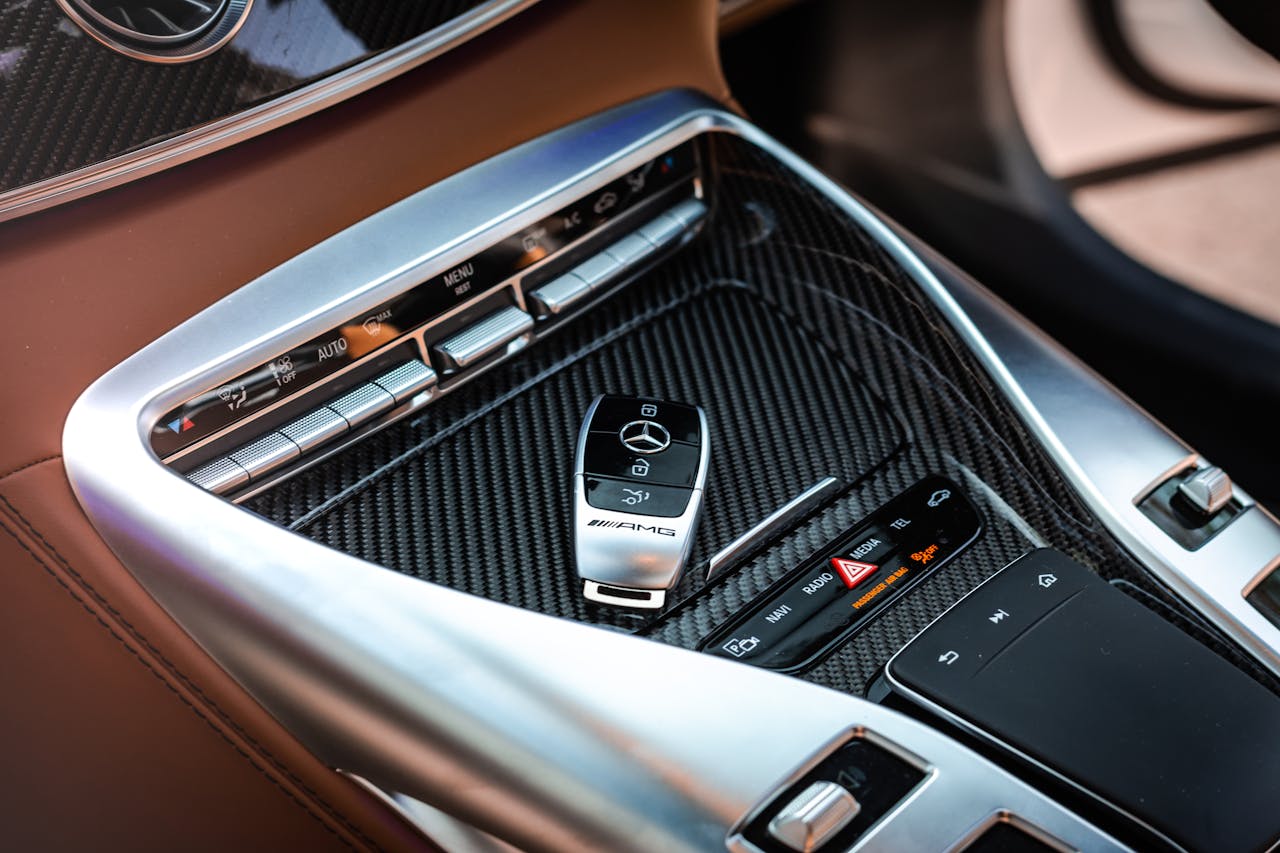 Close-up view of a luxury car's control panel featuring carbon fiber and chrome details with a key fob.