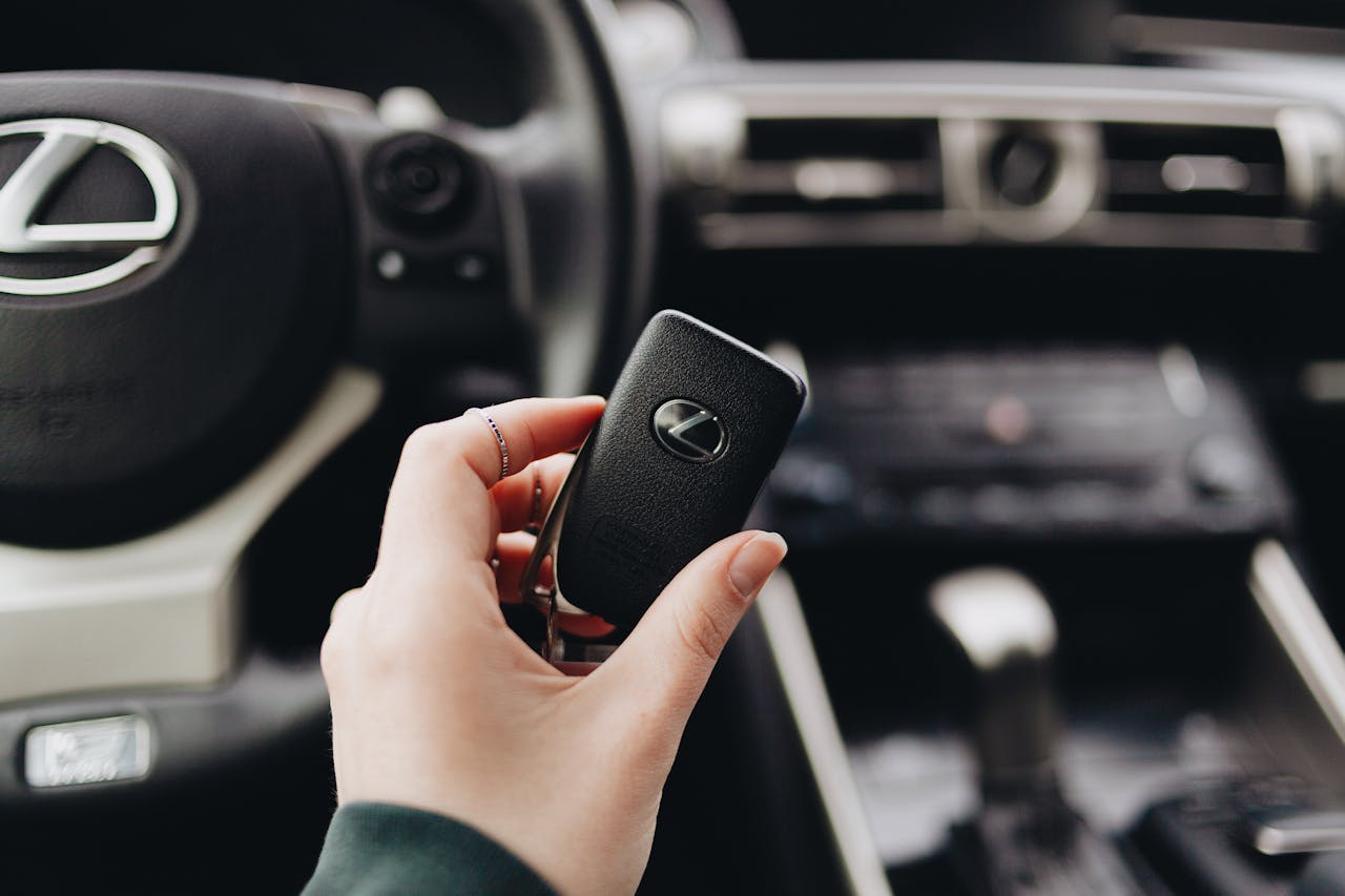 digital-01 Person holding a Lexus car key inside a luxury vehicle's interior, showcasing brand elegance.