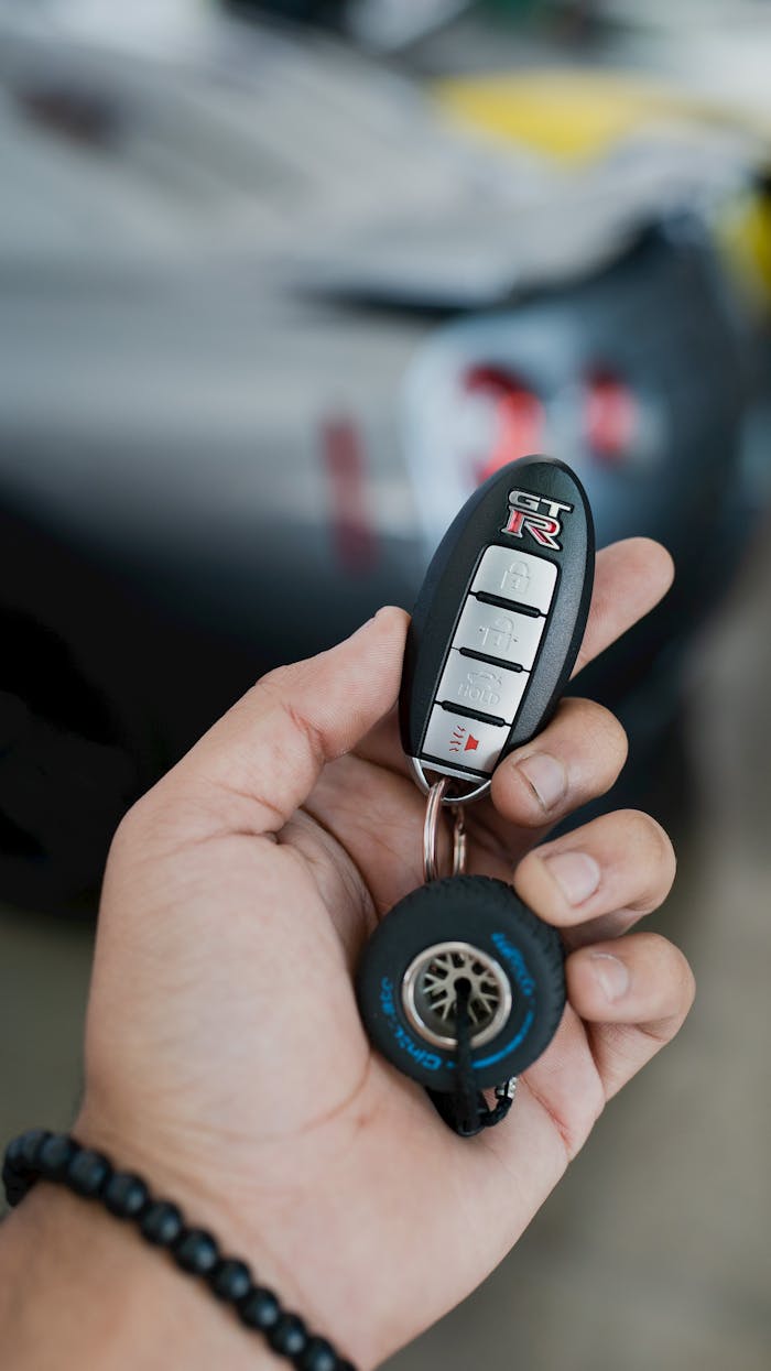 creative-03 Hand holding a Nissan GT-R key fob with a blurred car in the background.